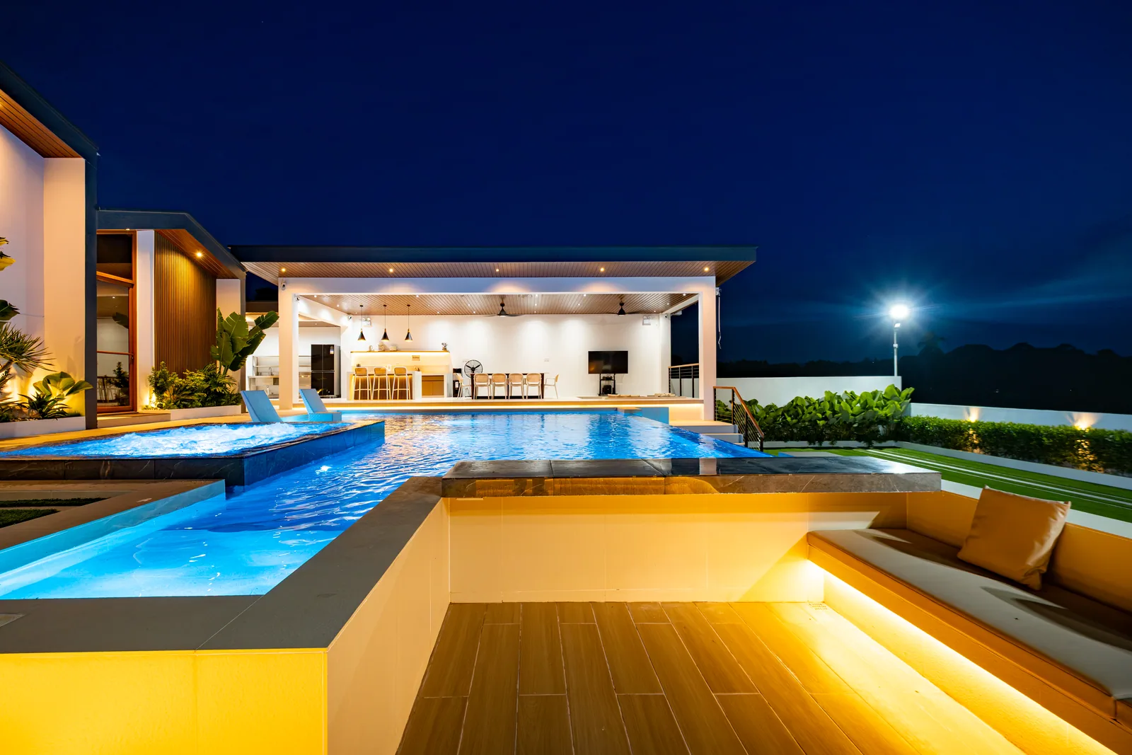 Poolside sunken lounge beside the infinity pool and jacuzzi at night.