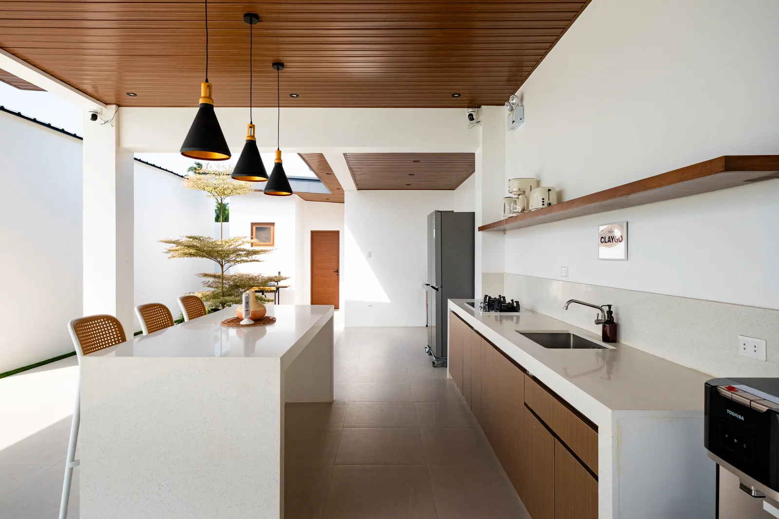 Modern outdoor kitchen with cooking facilities, refrigerator, dining island, and resort courtyard views at The Kasiden Private Resort.