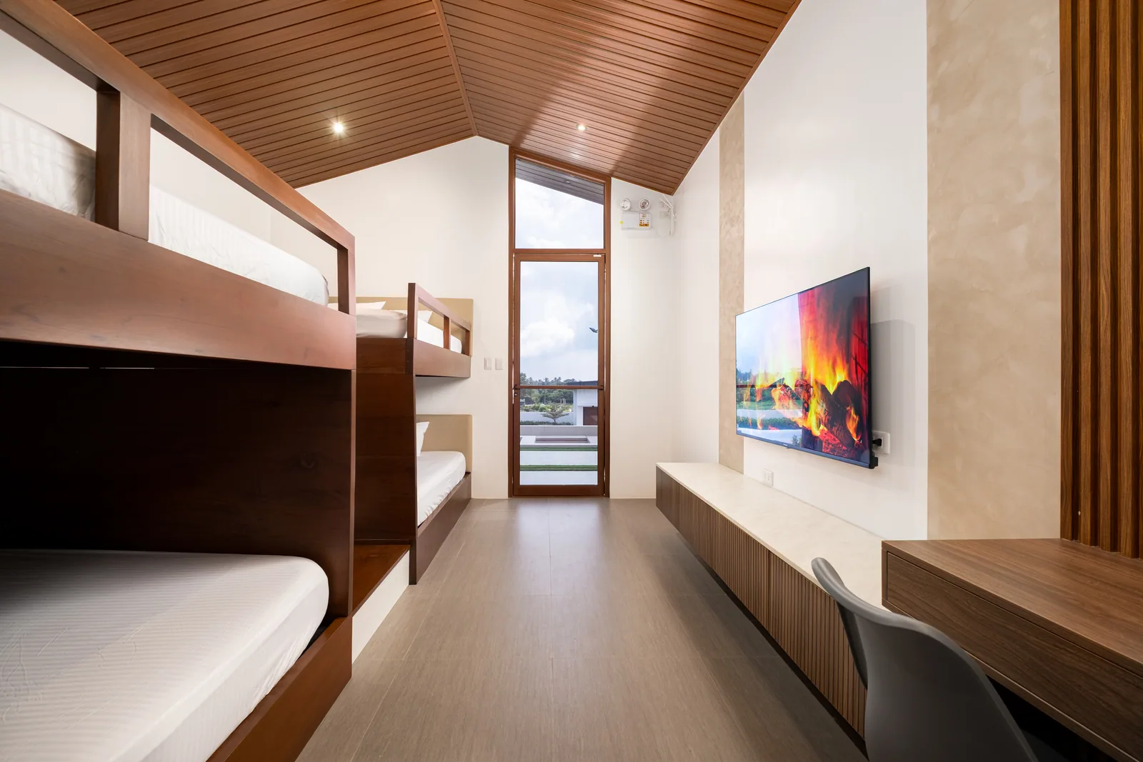 Bright and spacious villa room with four king-size beds, smart TV, work desk, and natural light at The Kasiden Private Resort.