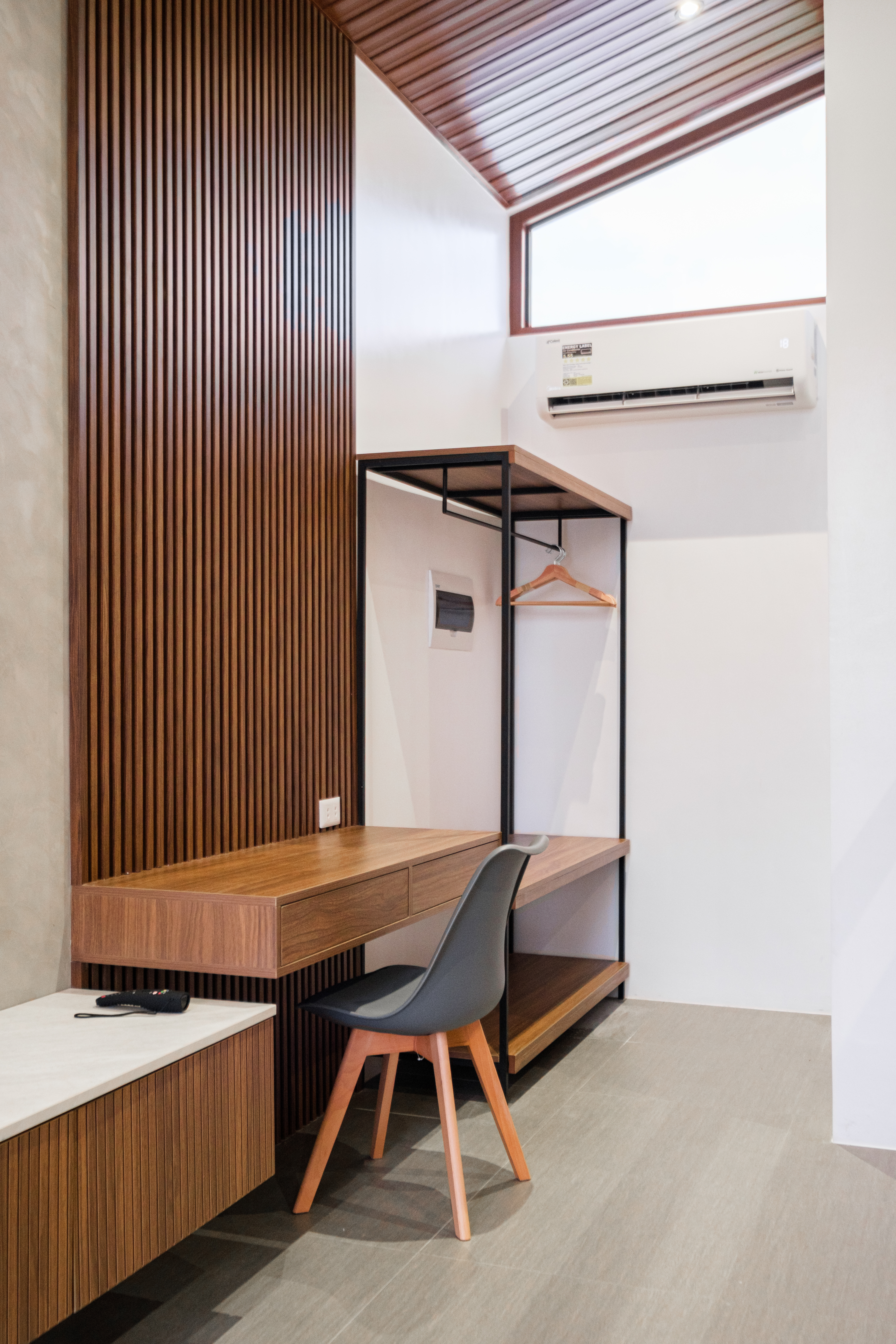 Modern villa workspace with desk, luggage storage, clothing rack, and air conditioning at The Kasiden Private Resort.