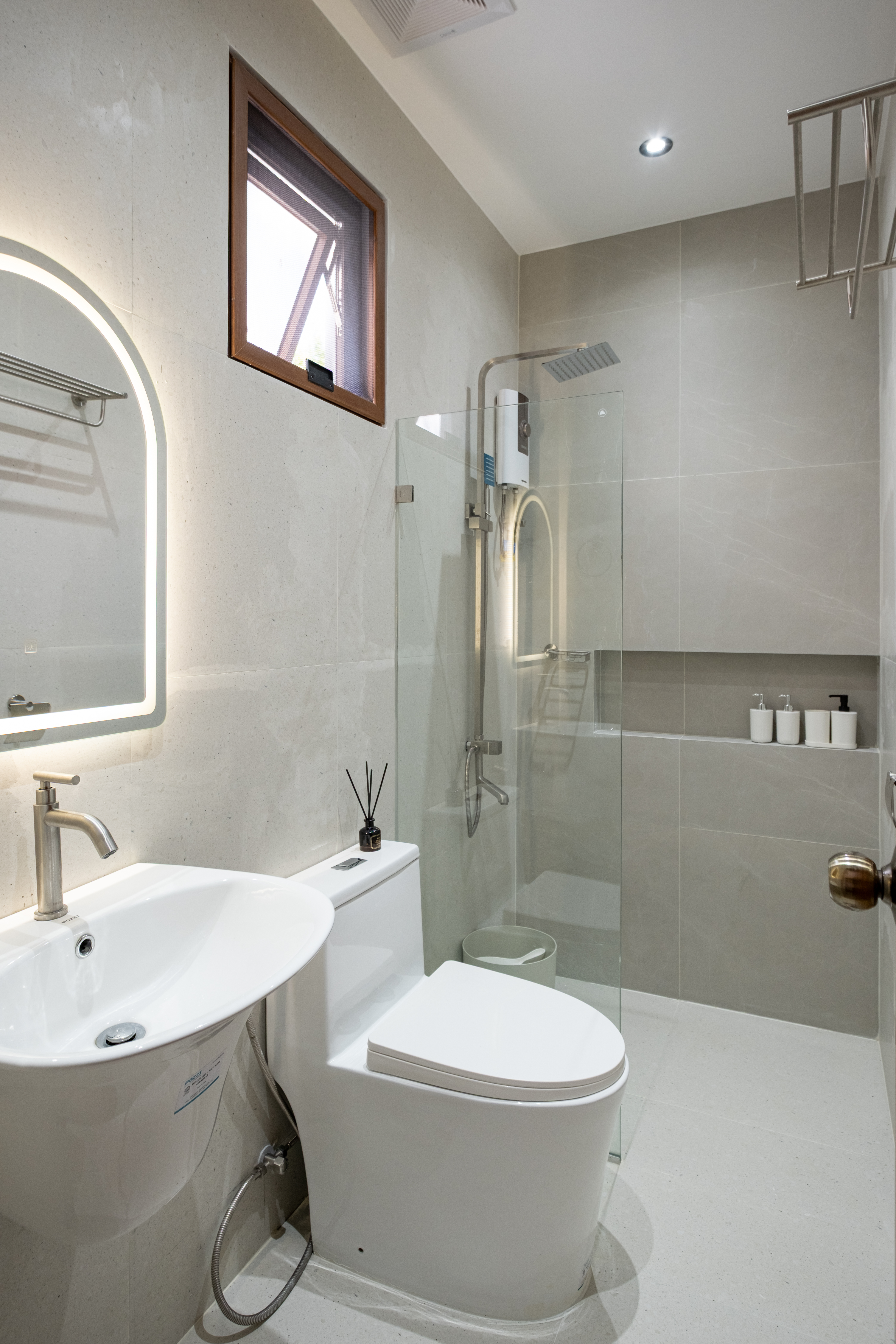 Modern ensuite bathroom featuring a rain shower, glass enclosure, illuminated mirror, and contemporary fixtures at The Kasiden Private Resort in Alfonso, Cavite.