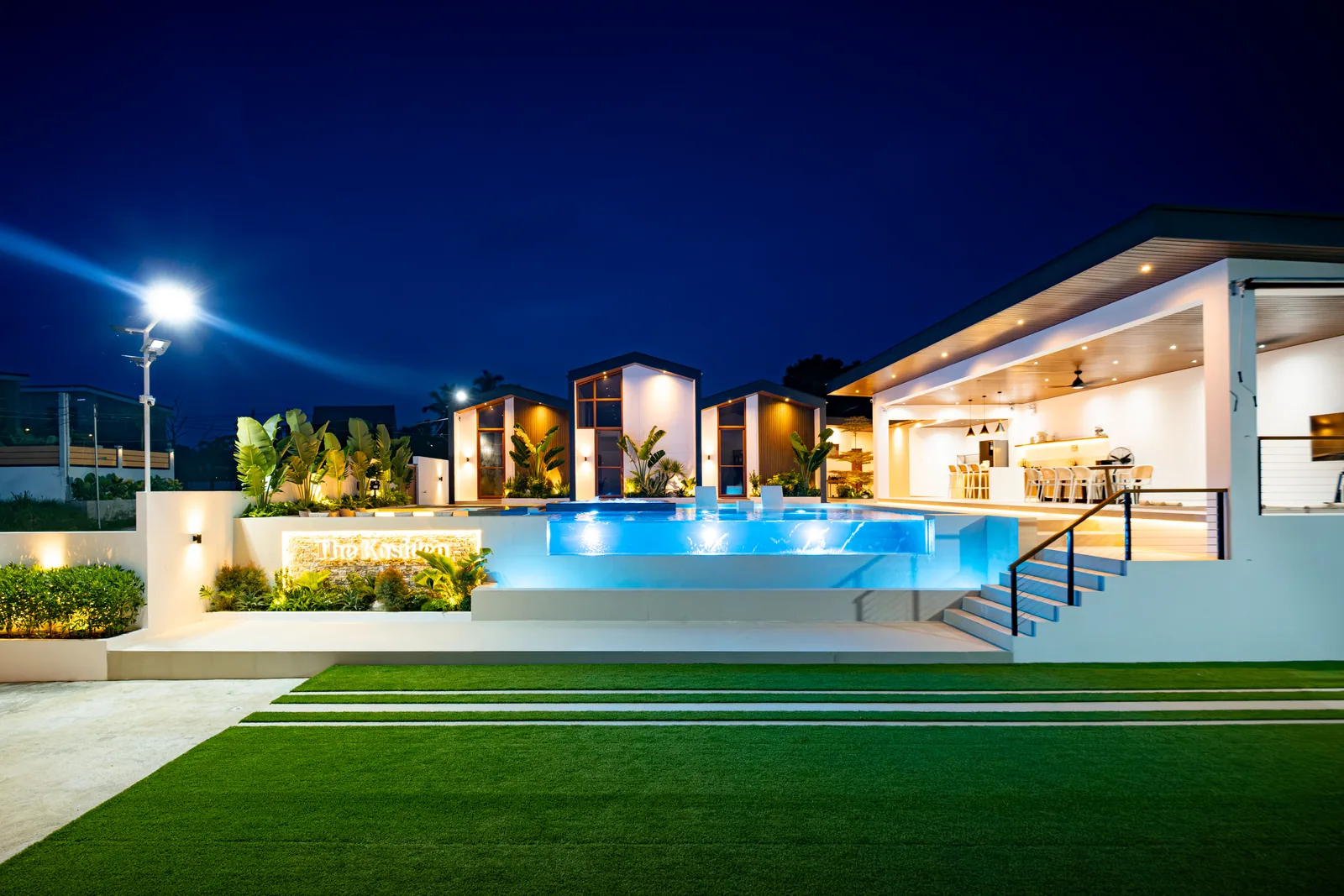 The Kasiden Private Resort illuminated at night with infinity pool, villas, and open-air gazebo.