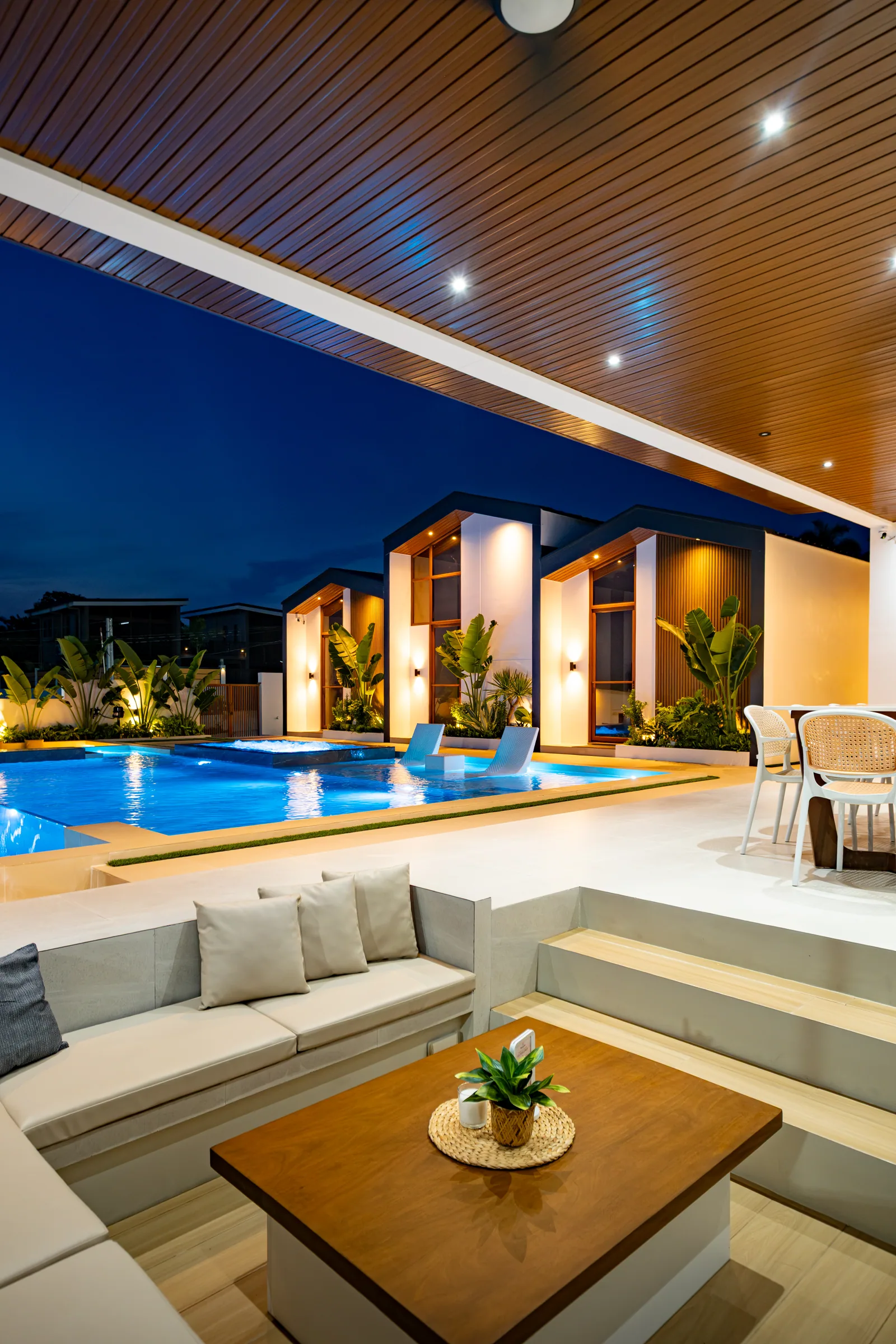 Cozy sunken seating area overlooking the illuminated pool and villas at night.
