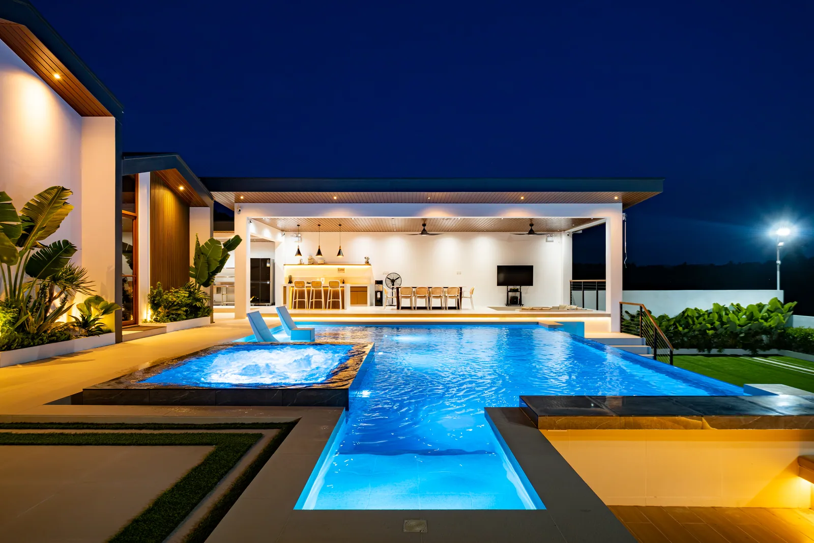 Infinity pool and open-air gazebo illuminated at night.