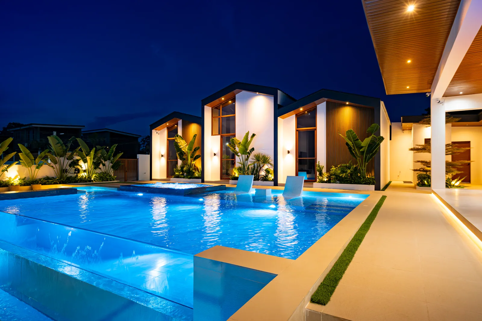 Illuminated infinity pool and villas at night.