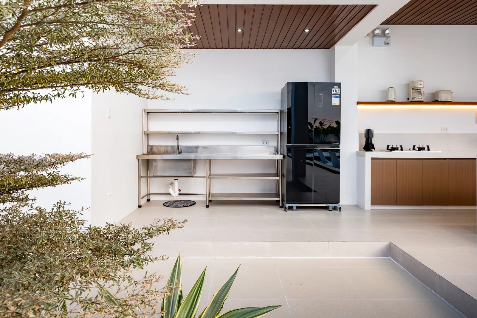 Dedicated dirty kitchen with stainless work area, refrigerator, and cooking facilities for guests at The Kasiden Private Resort.